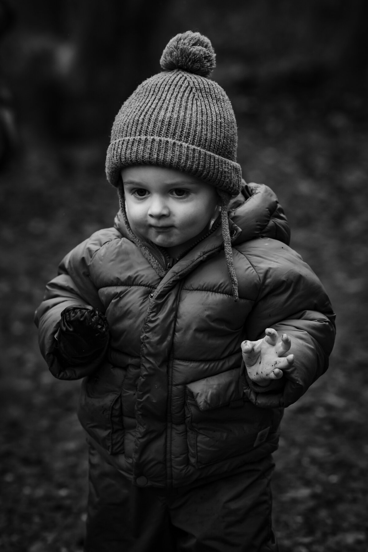 black and white image of little boy with bobble hat during winter family photoshoot