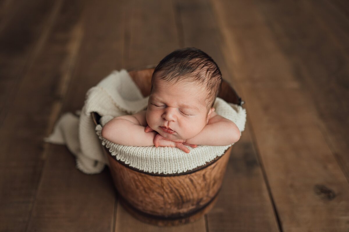 baby poses in bucket prop during newborn photography session