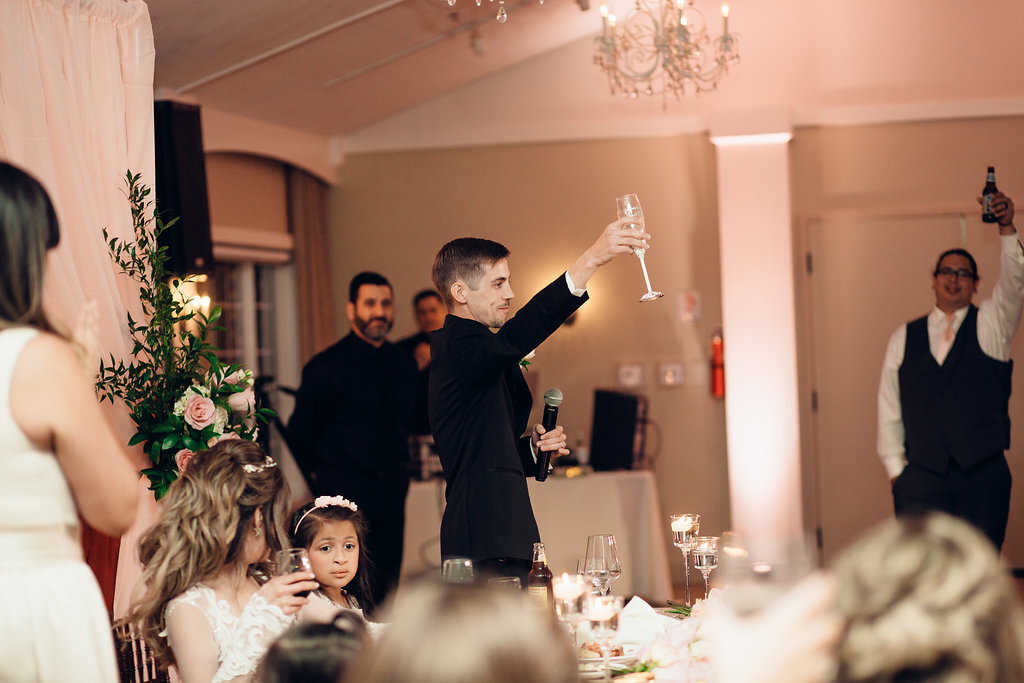 Wedding Photograph Of Groom In Black Suit Raising His Wine Glass To Everyone Los Angeles