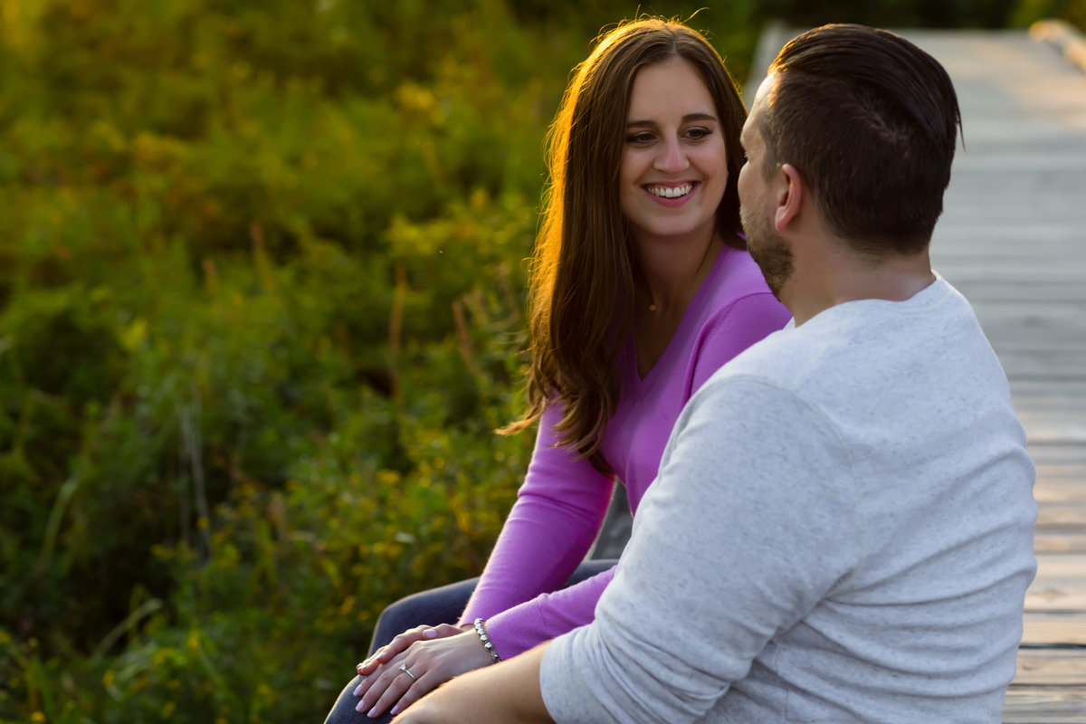 The couple sits on the wooden walkways at Kettle Cove Maine engagement session