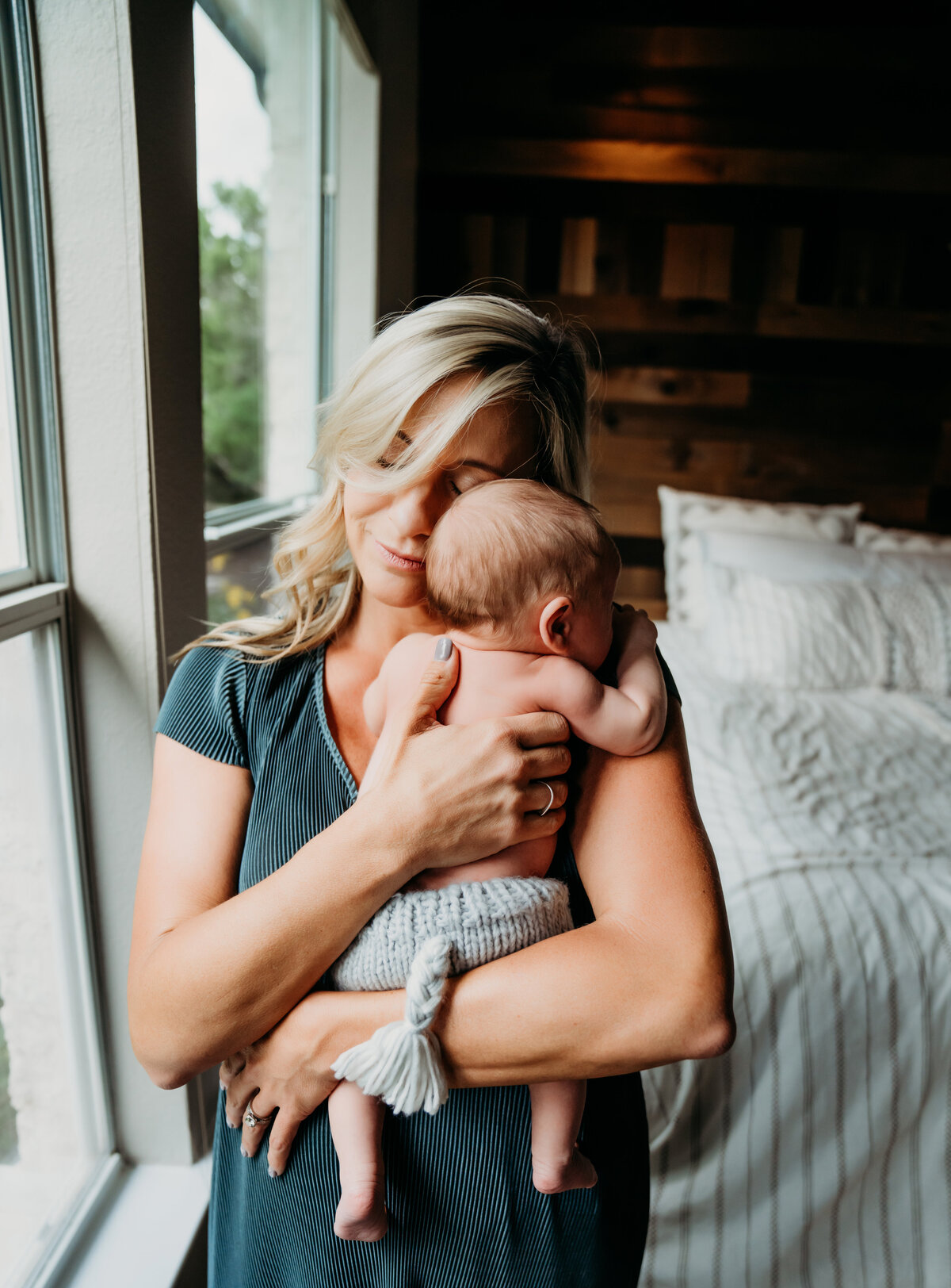 Newborn Photographer, a young mother holds baby to her chest