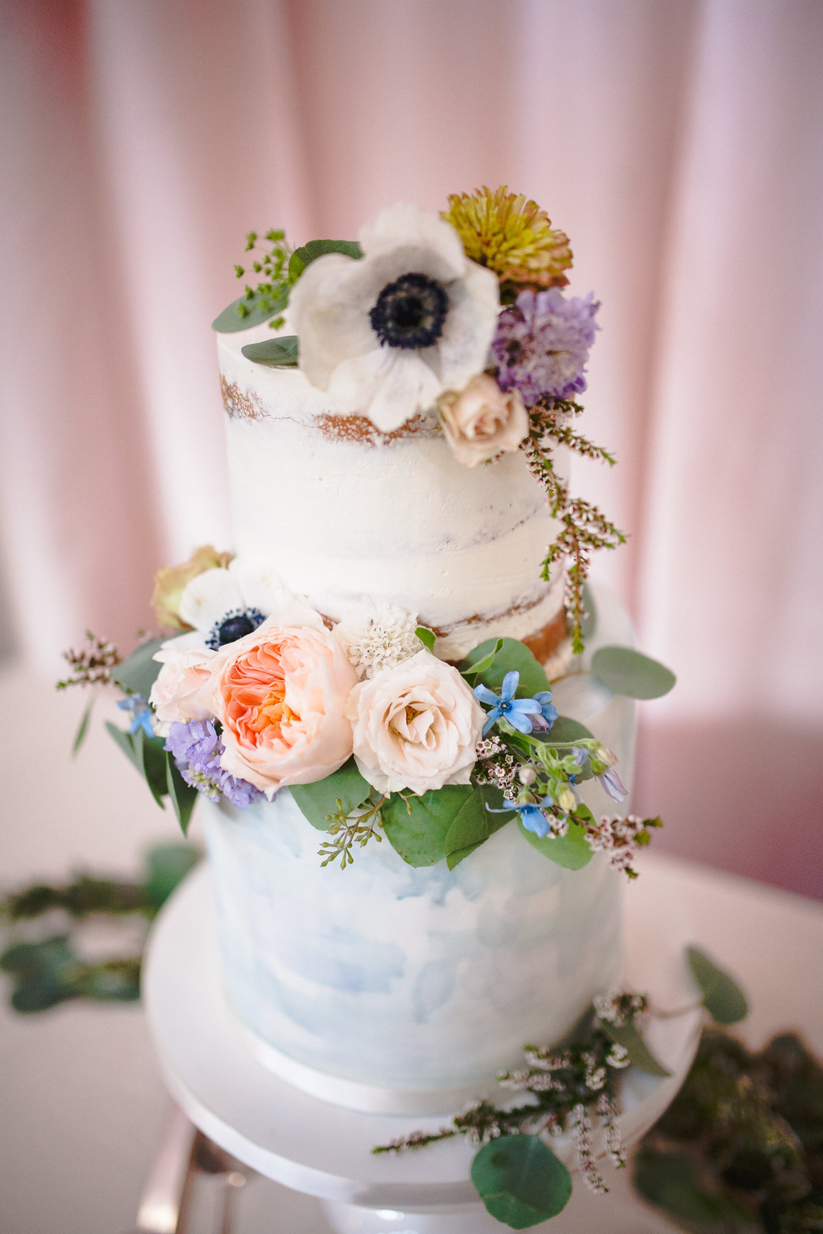 Multi tiered wedding cake with floral accents at a Missouri vineyard.