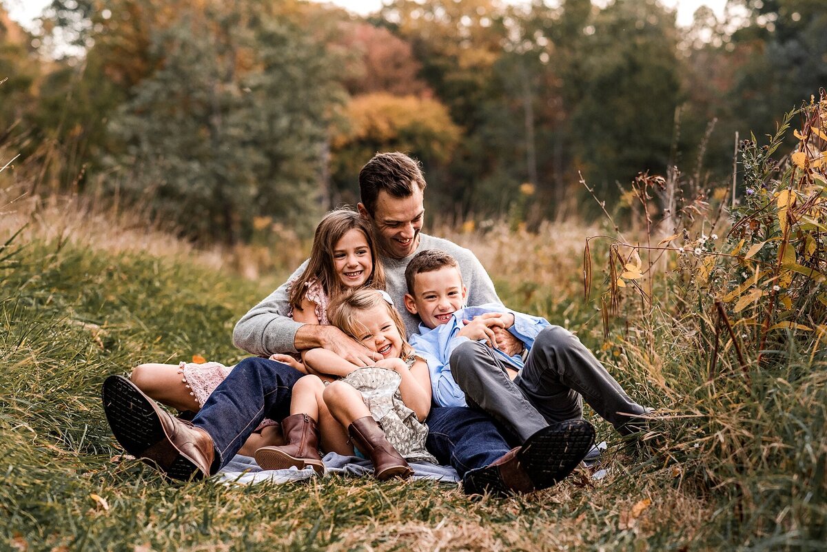 Dad with kids laughing in field