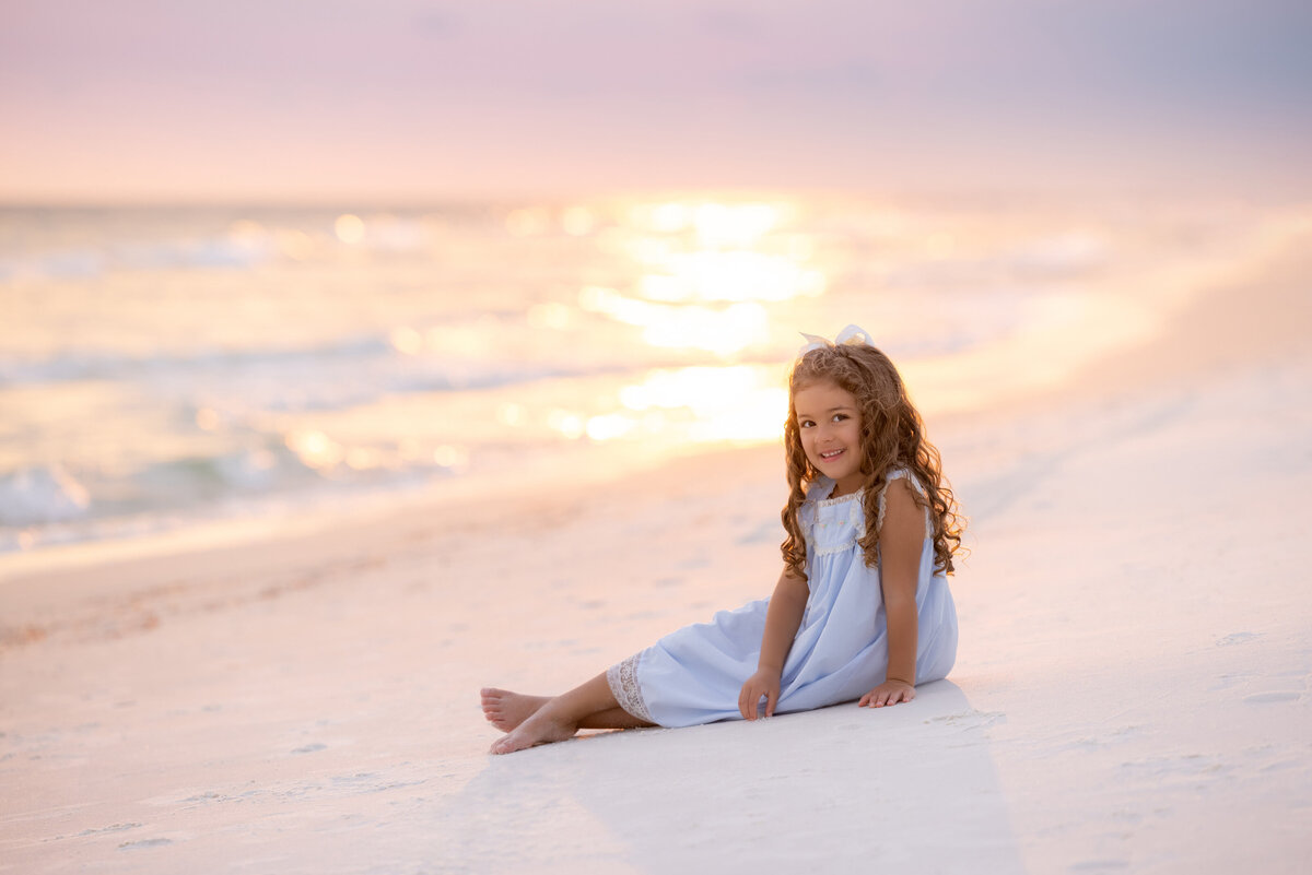 A small girl sitting in the sand