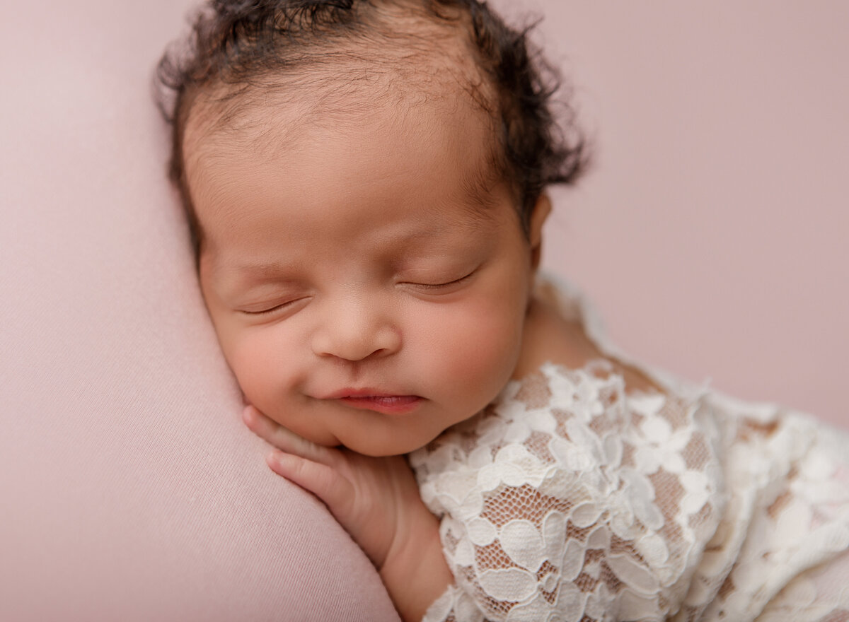 Smiling newborn in a lace onesie