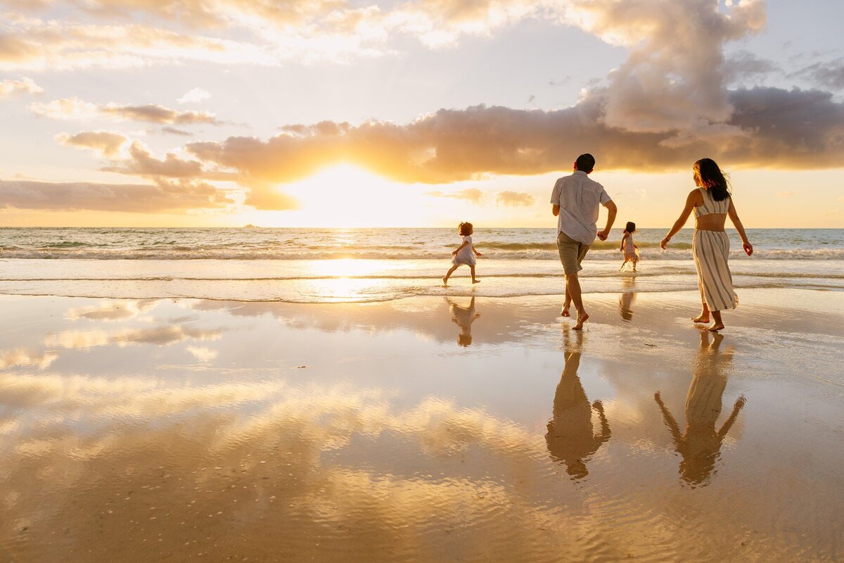 family of 4 plays along  the shallows of kailua beach at sunrise