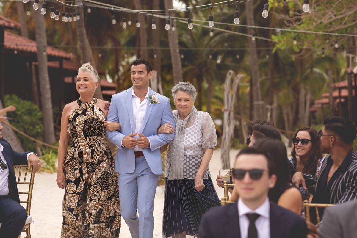 Groom walking down the aisle with mothers at  Riviera Maya wedding.