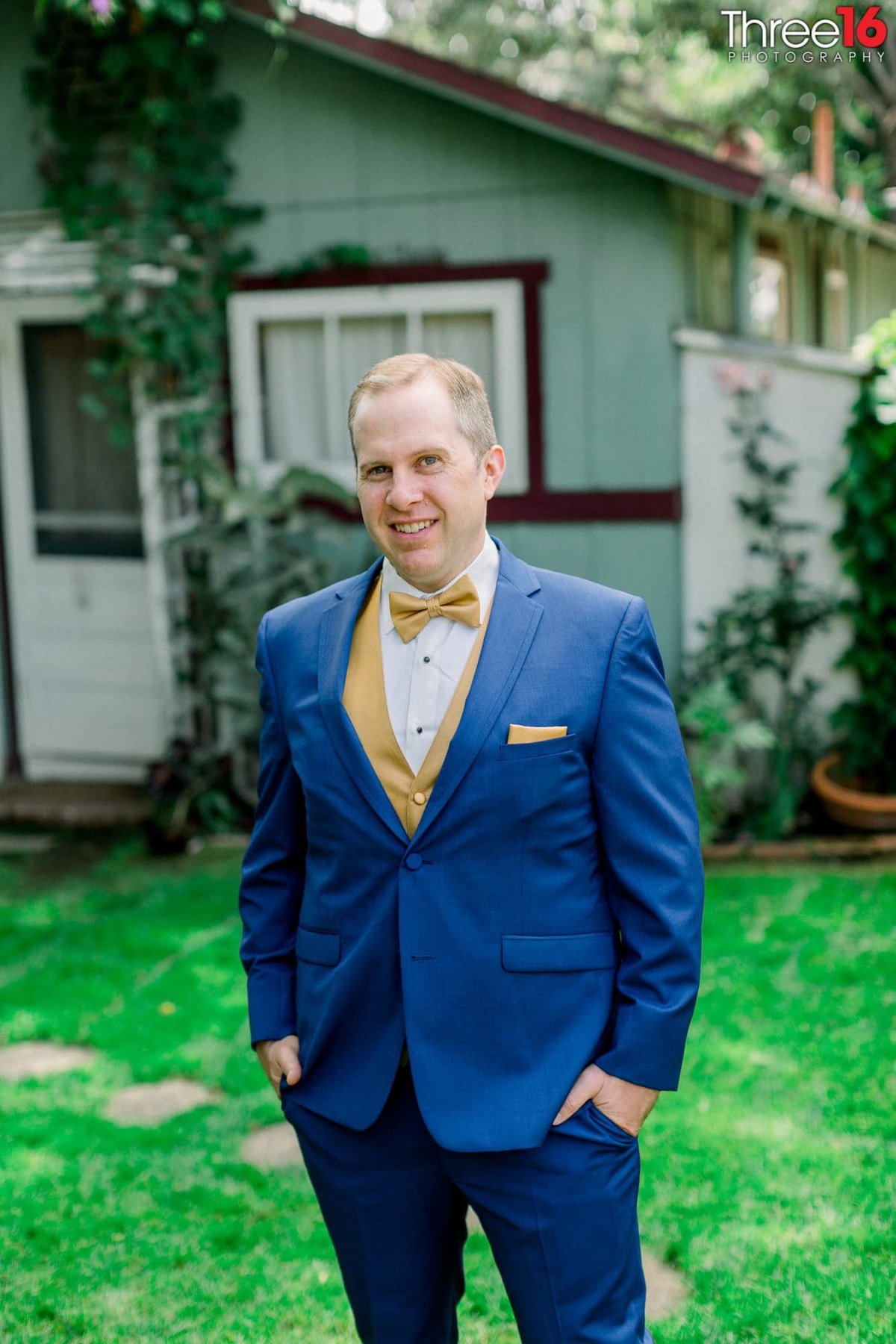 Groom poses for the wedding photographer with blue suit and yellow vest