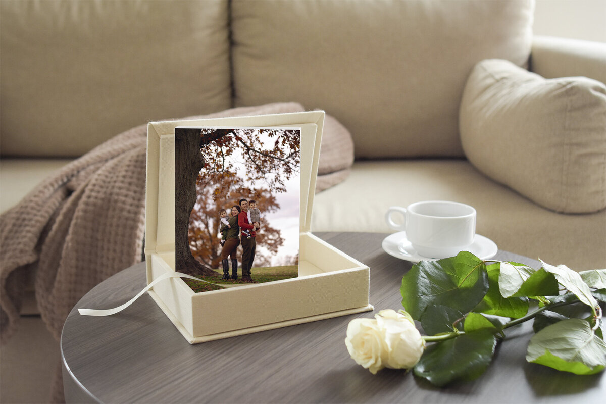 A family photo printed stands up in a fabric covered box on a coffee table