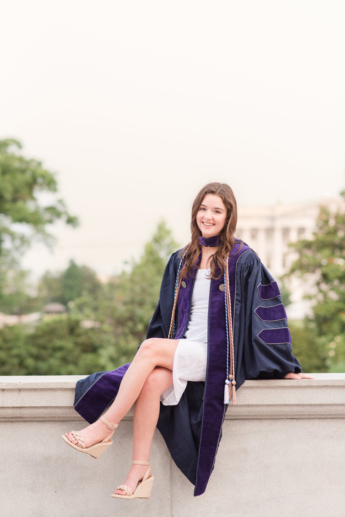 grad sitting on ledge  in gown