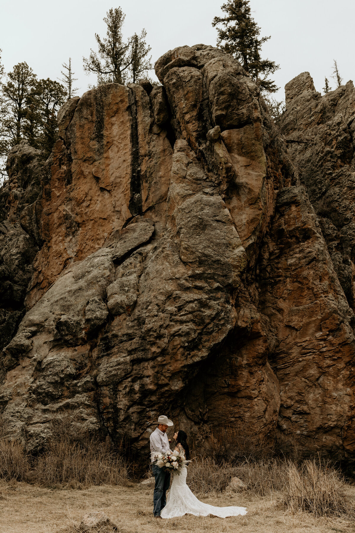 bride and groom standing in front of red rocks in Jemez Springs, NM