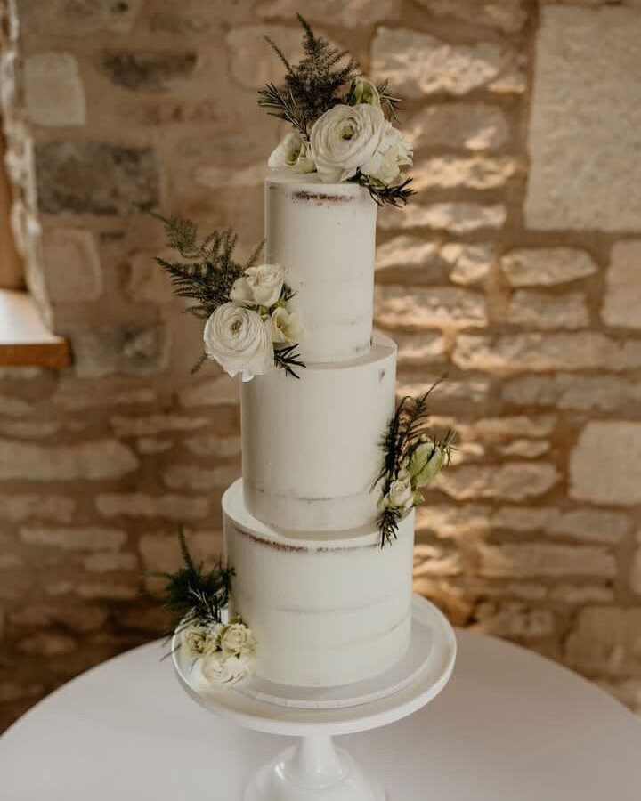 Semi-naked wedding cake with abundance of fresh flowers