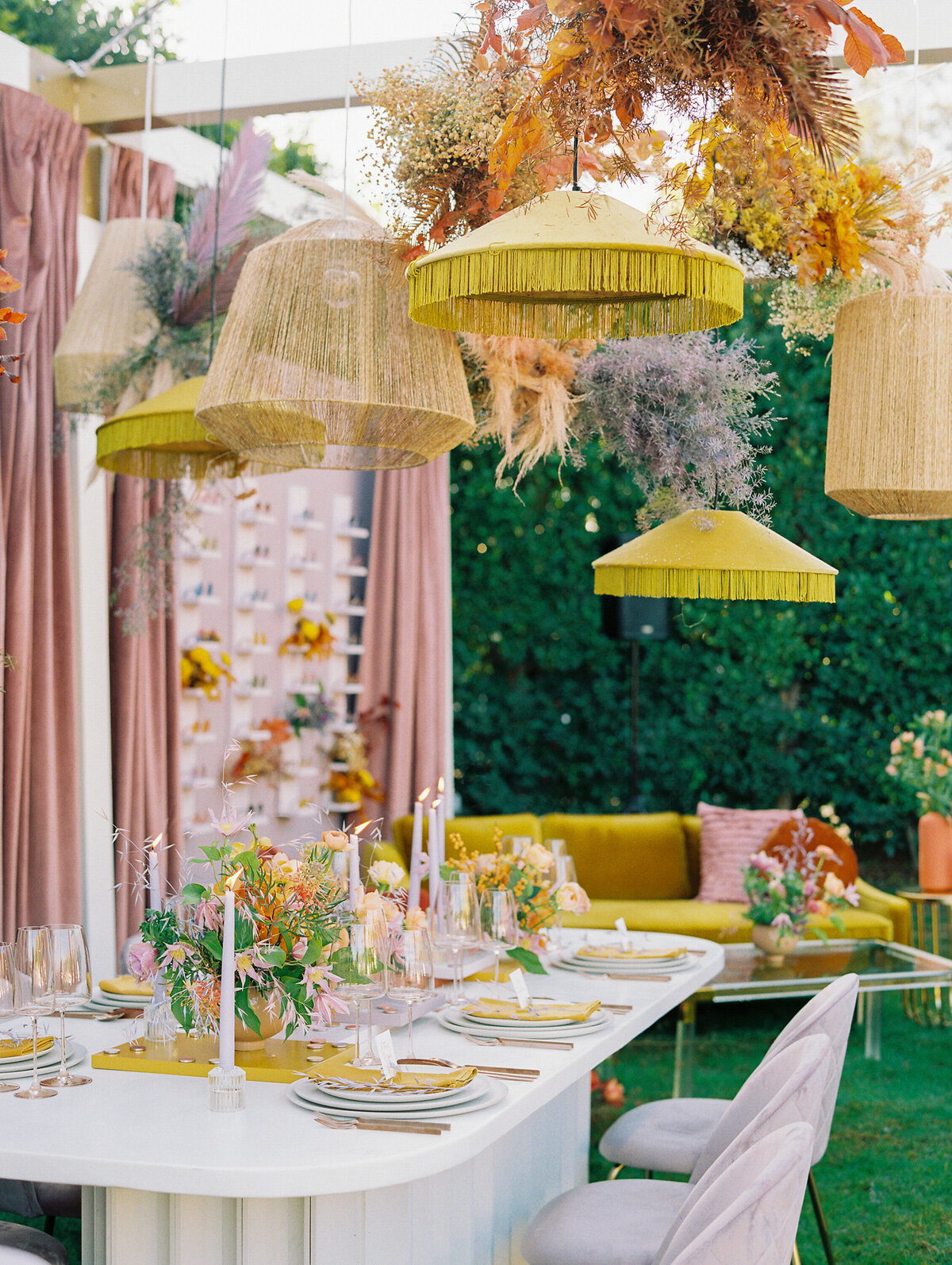 seating area with yellow sofa and rust colored chair adorned with flowers and seating chart with sunglasses for guests.