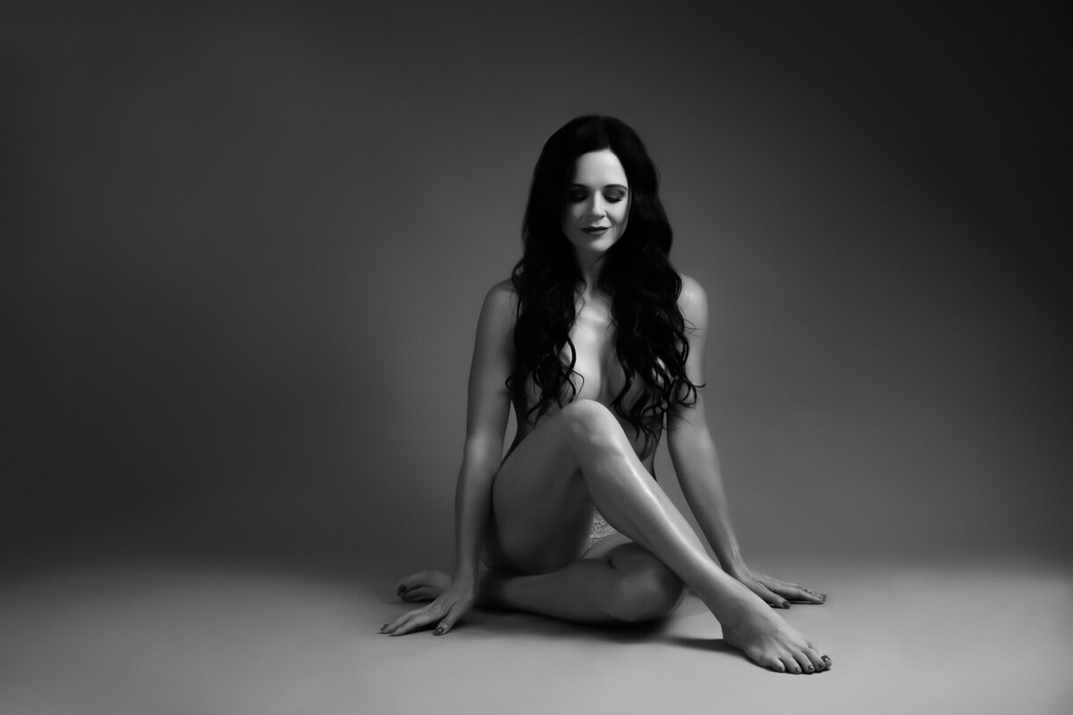 woman posing on the floor covering her boobs with her long dark hair