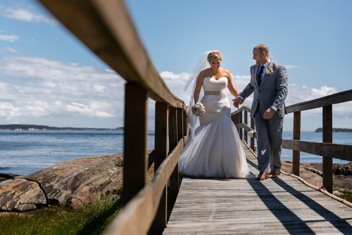 The bride and groom walk along the dock in Harpswell Maine