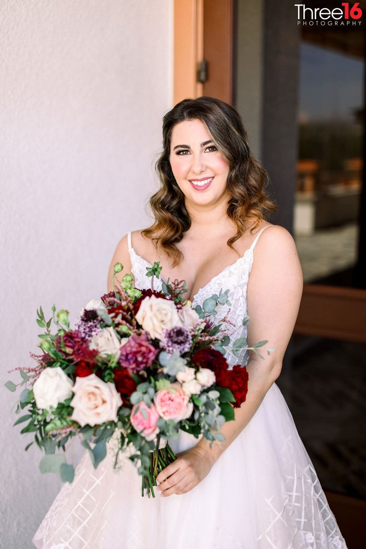 Bride poses is her wedding gown holding her beautiful large bouquet of flowers