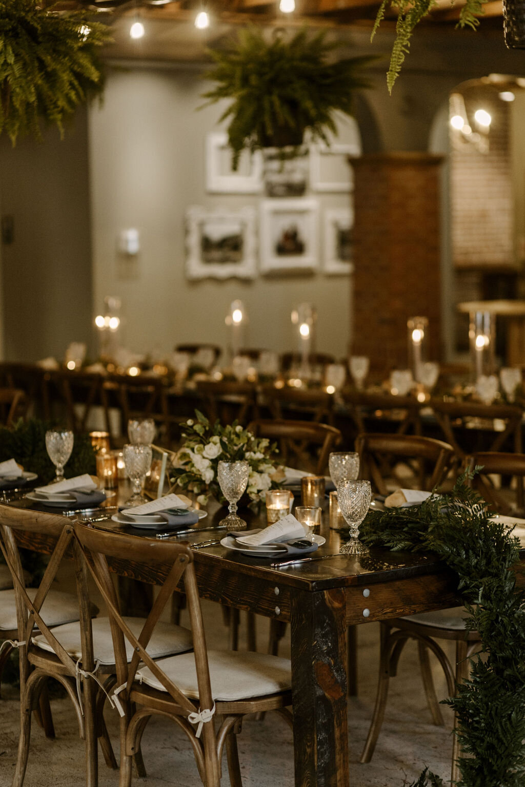 Wedding reception tables with greenery, candles and gray napkins