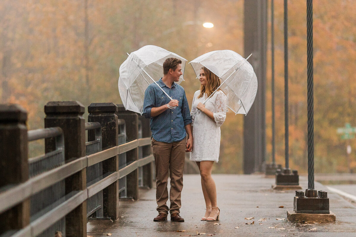 PNW rainy fall engagement session in mountains near Seattle WA with clear umbrellas and white dress photo by Joanna Monger Photography