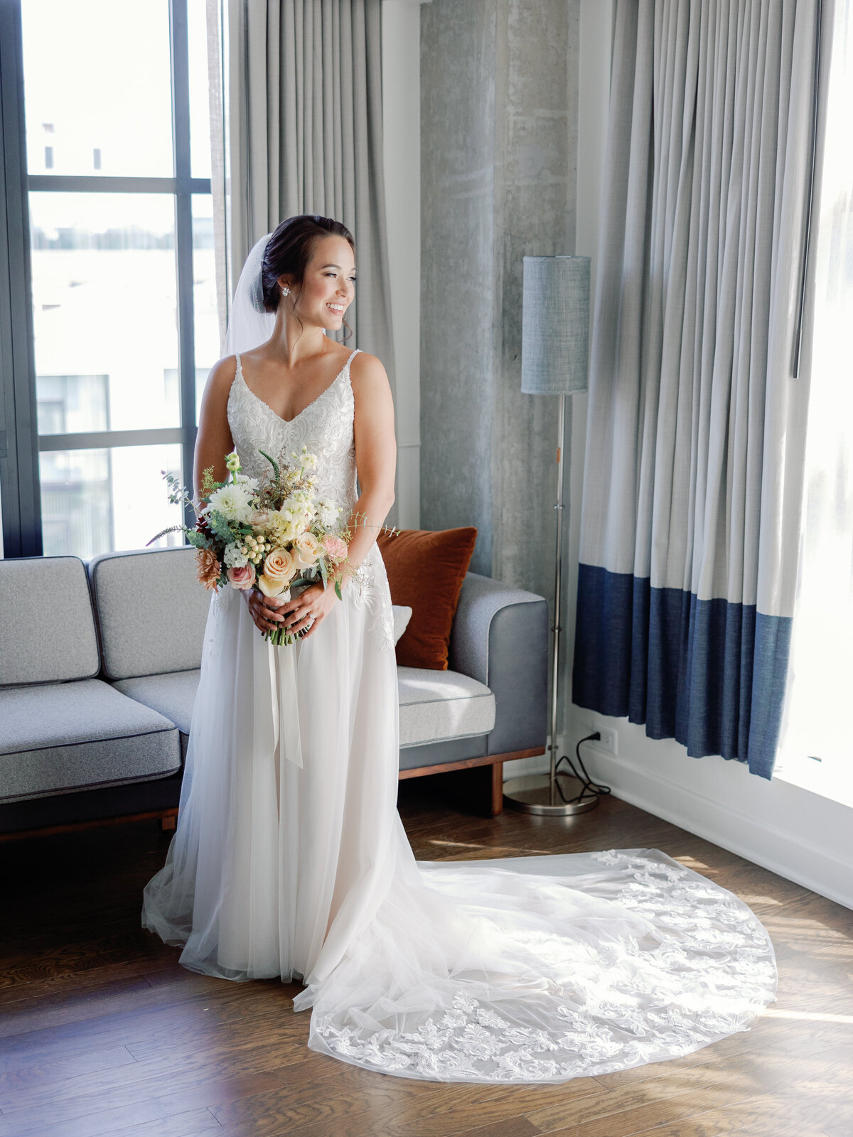 A full body portrait of the bride in her wedding dress as she holds her bouquet at her waist
