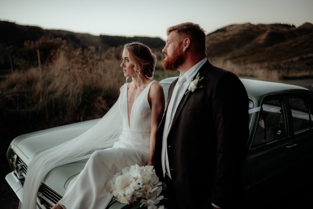 bride and groom sitting on car bonnet
