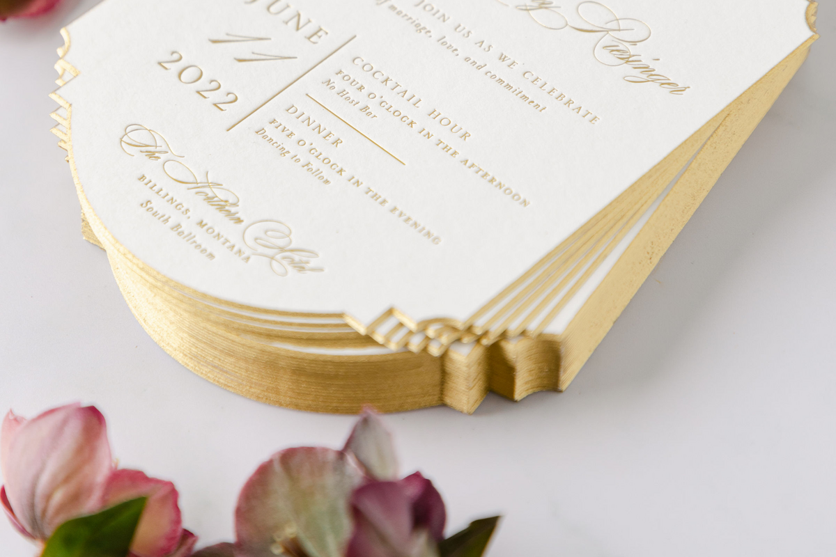 Detail shot of 50th anniversary invitations showcasing the precise cut, deep gold foil accents, and beveled gold edges.