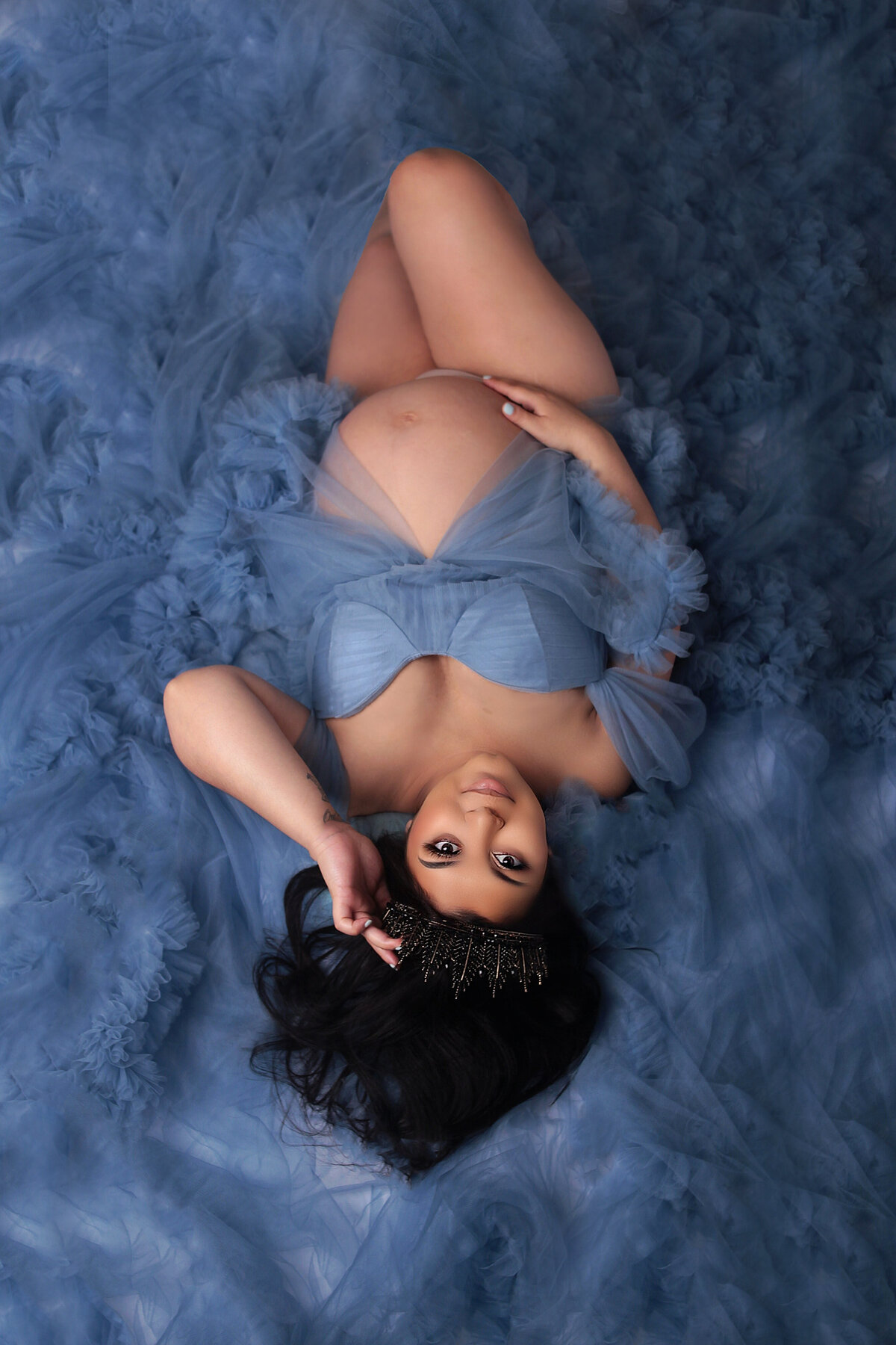 Women laying down, wearing blue gown during glam maternity photoshoot in Mount Juliet tennessee photography studio