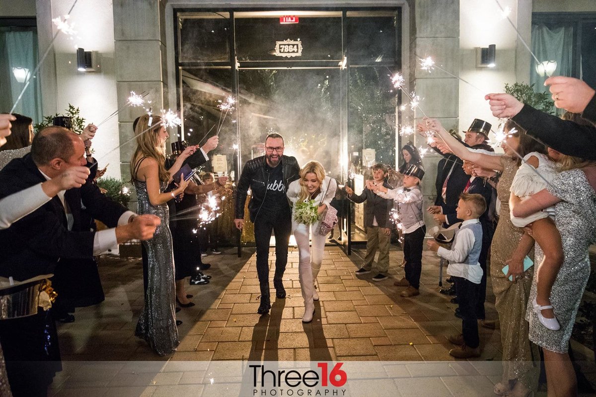 Bride and Groom exit the Settebello Pizzeria to a tunnel of guests hold up sparklers