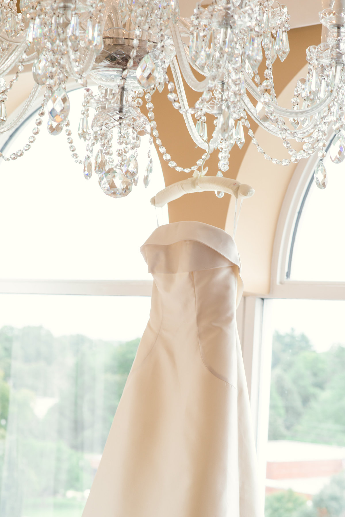 photo of bridal gown hanging on chandelier from inside The Garden City Hotel