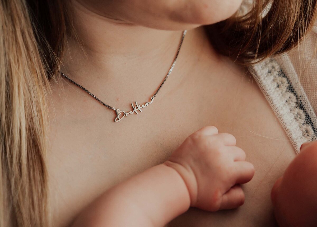 Maddie Rae Photography baby's hand on mamas chest. mom is wearing a necklace with his name on it