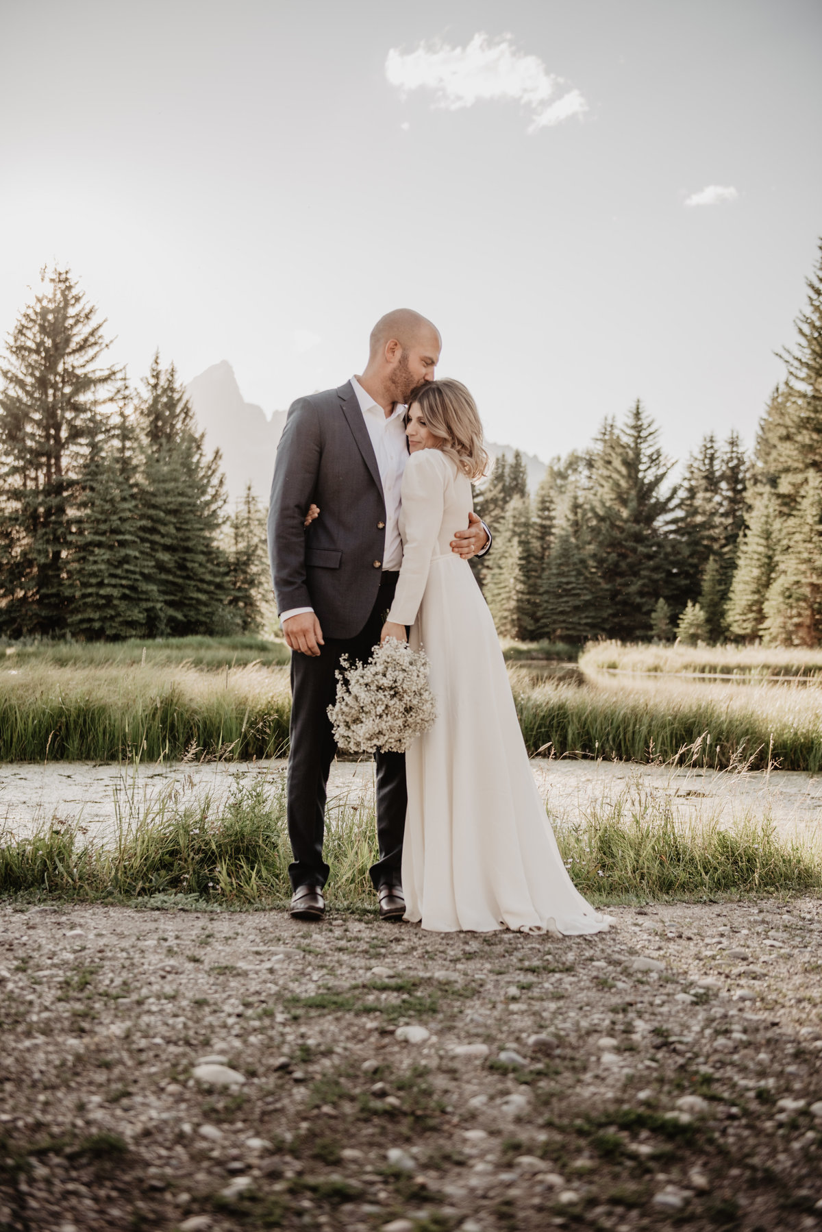 jackson wyoming photographer captures jackson hole wedding pictures with groom holding his bride during his Teton elopement, bride snuggles into her groom