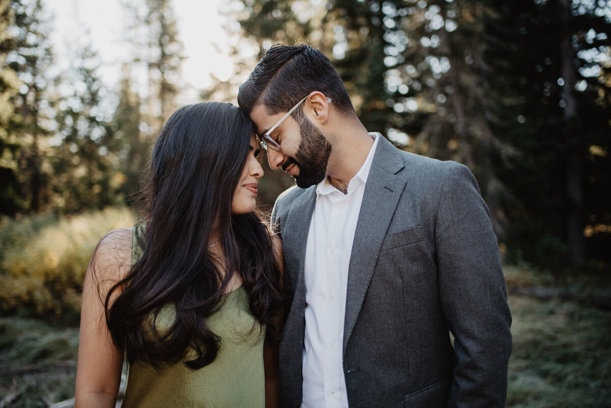 photographers in jackson hole captured romantic engagement pictures with man and woman standing next to each other with their fore heads toughing and gently smiling as they close their eyes in Jackson Hole during the fall for an engagement session