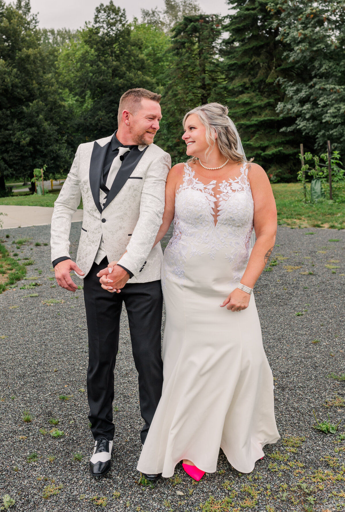 Bride and groom looking at each other smiling, hips touching and holding hands.