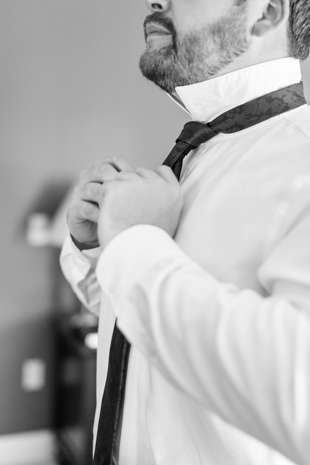 groom tying tie before wedding