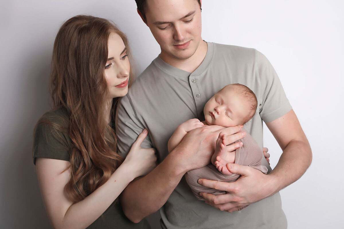 newborn-baby-boy-wrapped-in-brown-sleeping-in-his-dads-arm-for-the-family-baby-shoot
