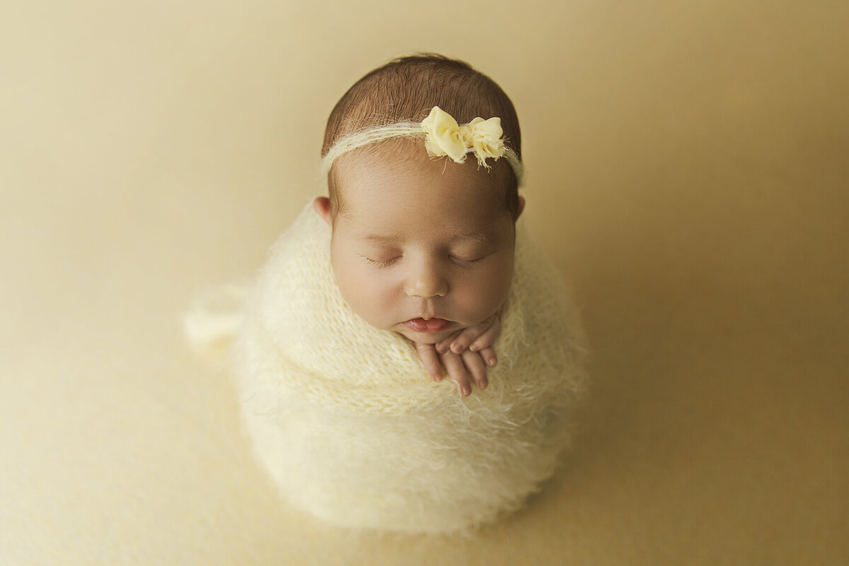 newborn baby in yellow textured wrap potato sack