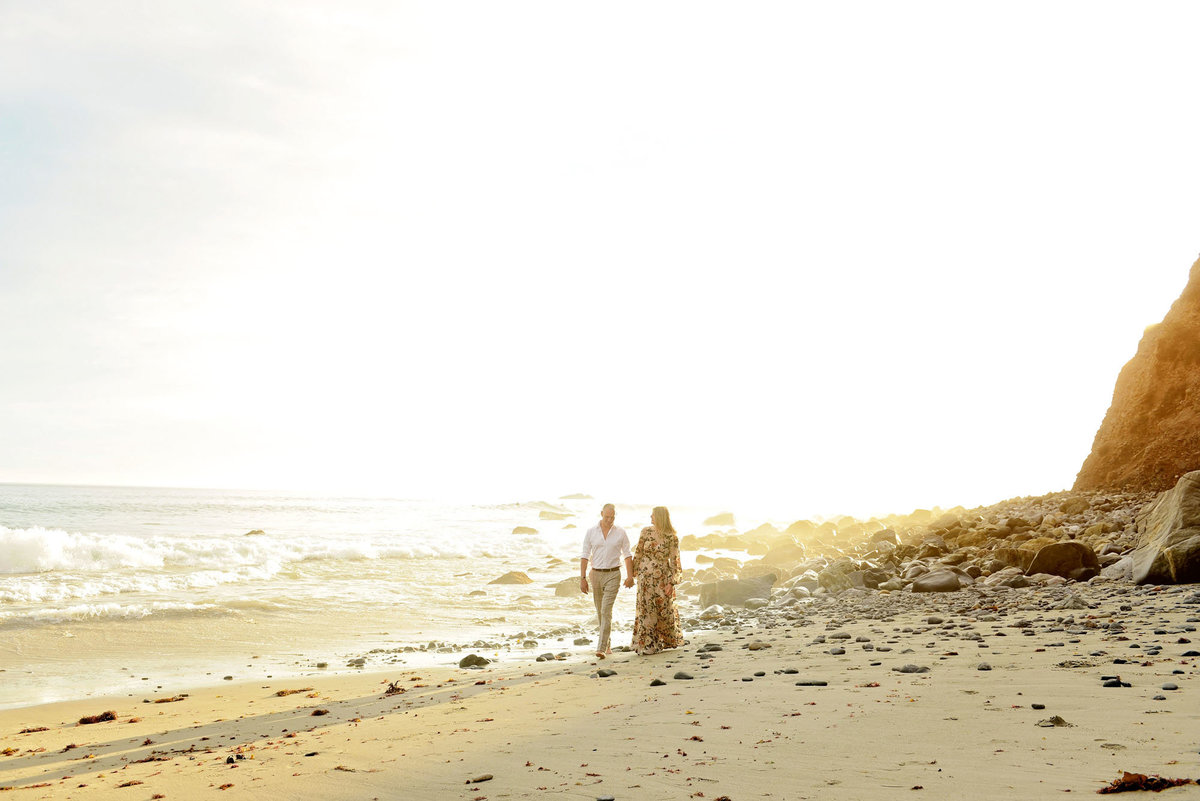Stylish couple walking on Dana Point beach for engagement