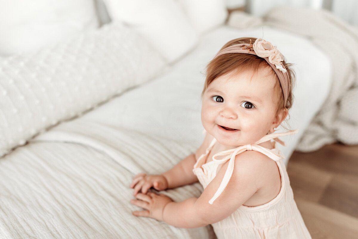 baby girl leaning on daybed looking at photographer Alyssum Hutchison