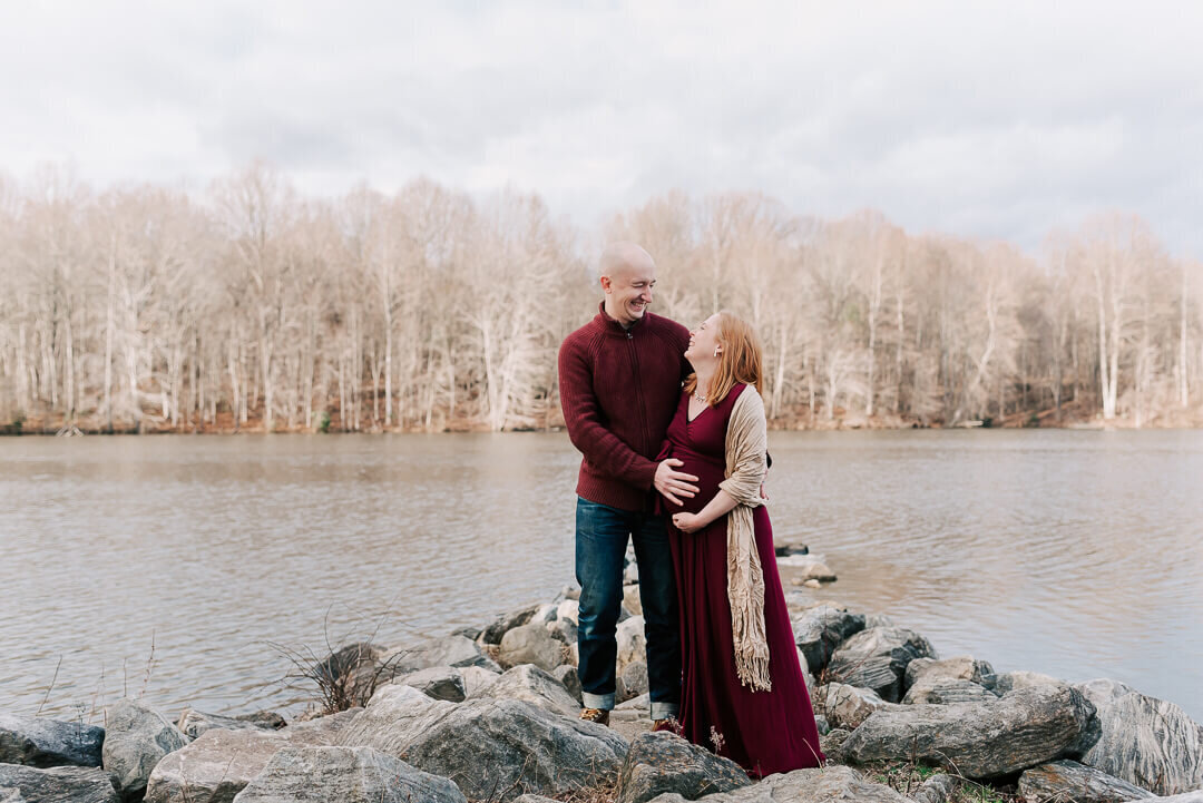 A couple dressed in burgundy laughing together, taken by a northern virginia maternity photograper