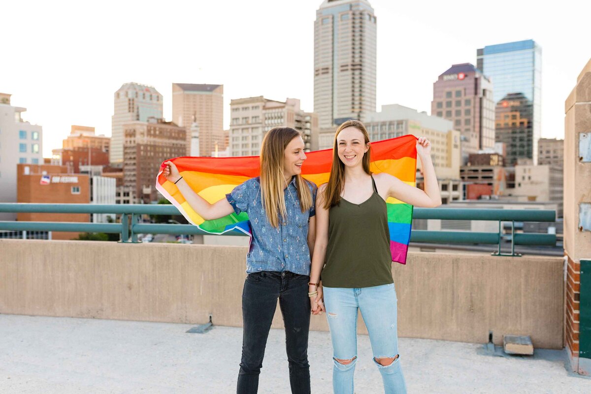 Lesbian couple holding LGBT Pride flag in parking garage
