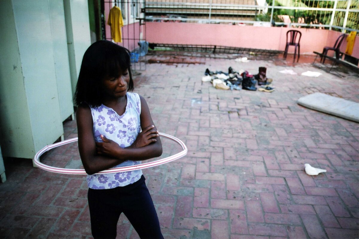 Girl in an orphanage hula hoops in orphanage patio