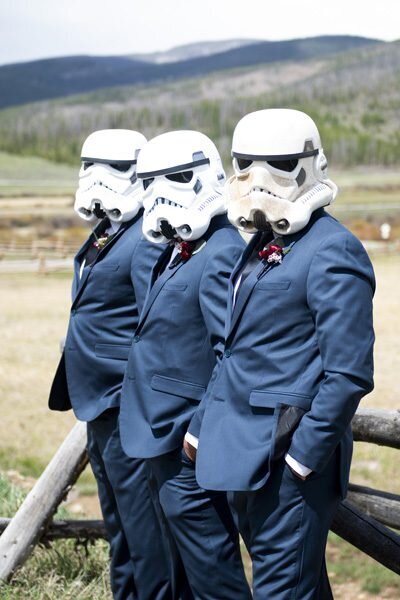 Three groomsmen stare at the camera wearing masks from Star Wars.