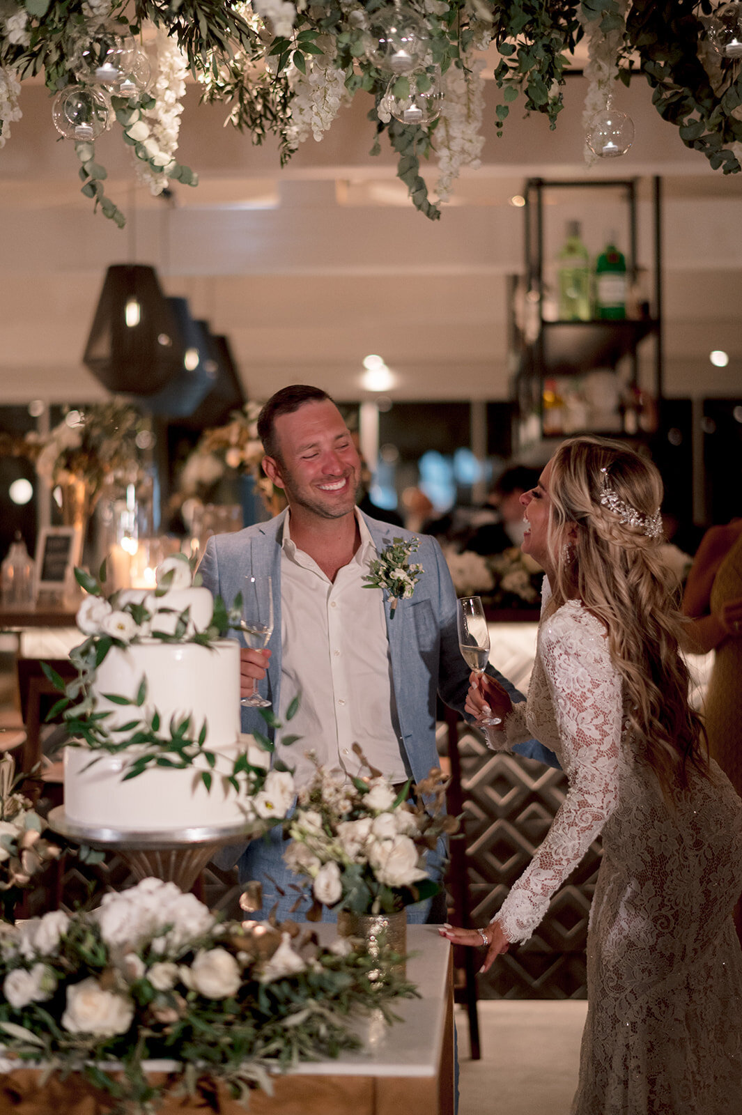 bride and groom laugh as they cut their wedding cake at greece wedding venue photo by cait fletcher photography