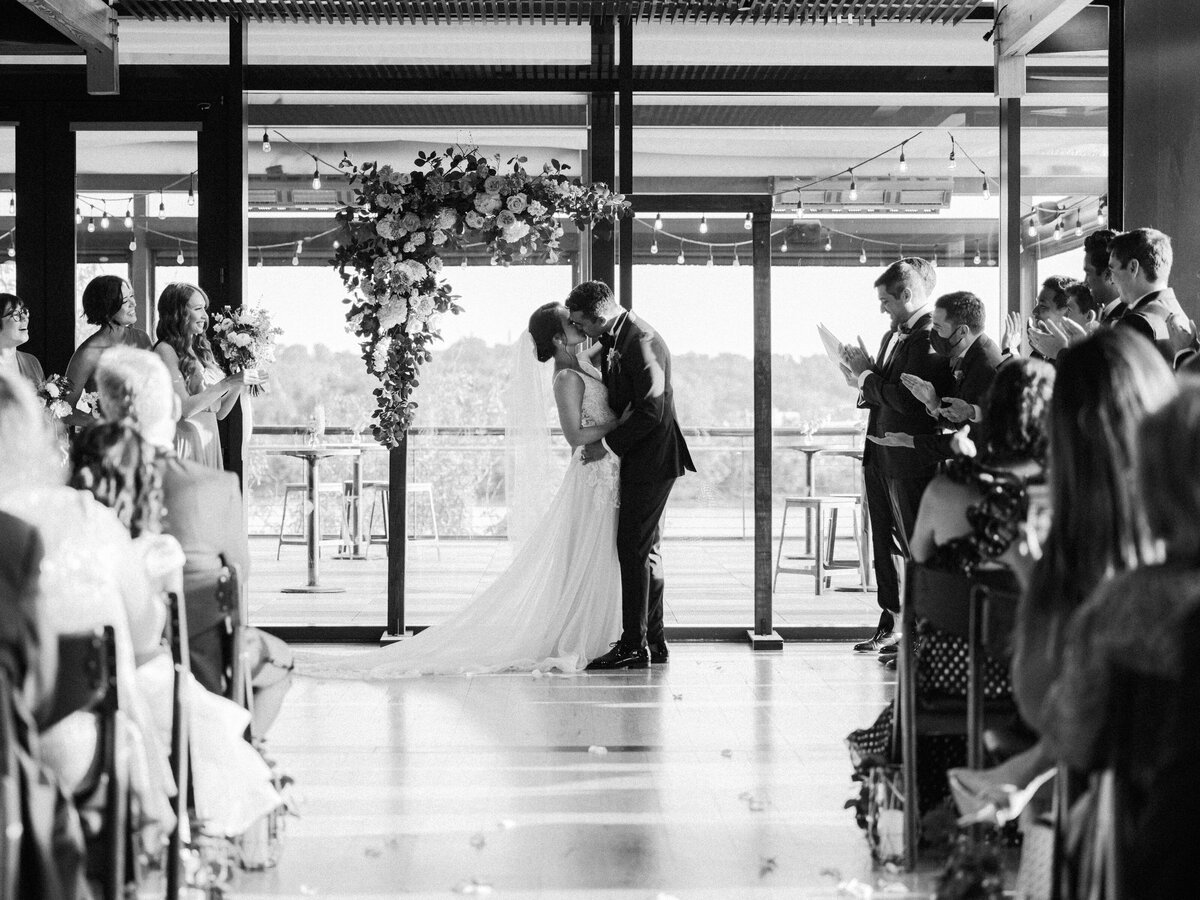 A bride and groom share their first kiss as a married couple during their wedding ceremony at district winery in washington dc