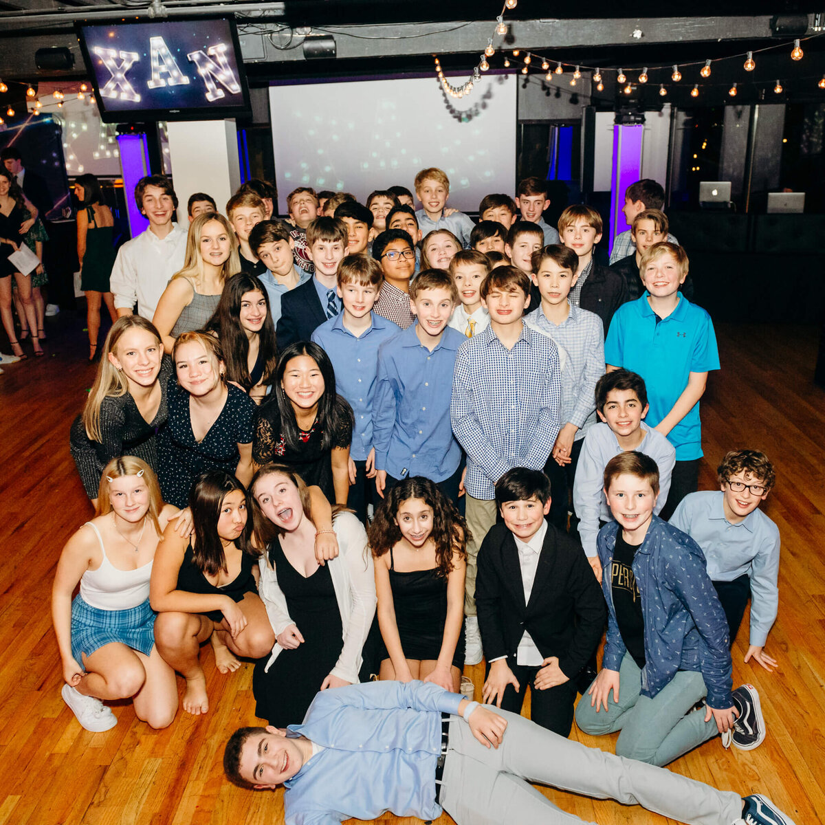 A large group of teenage friends come together on the dance floor for a group photo during some Bellevue Bar and Bat Mitzvah Photography