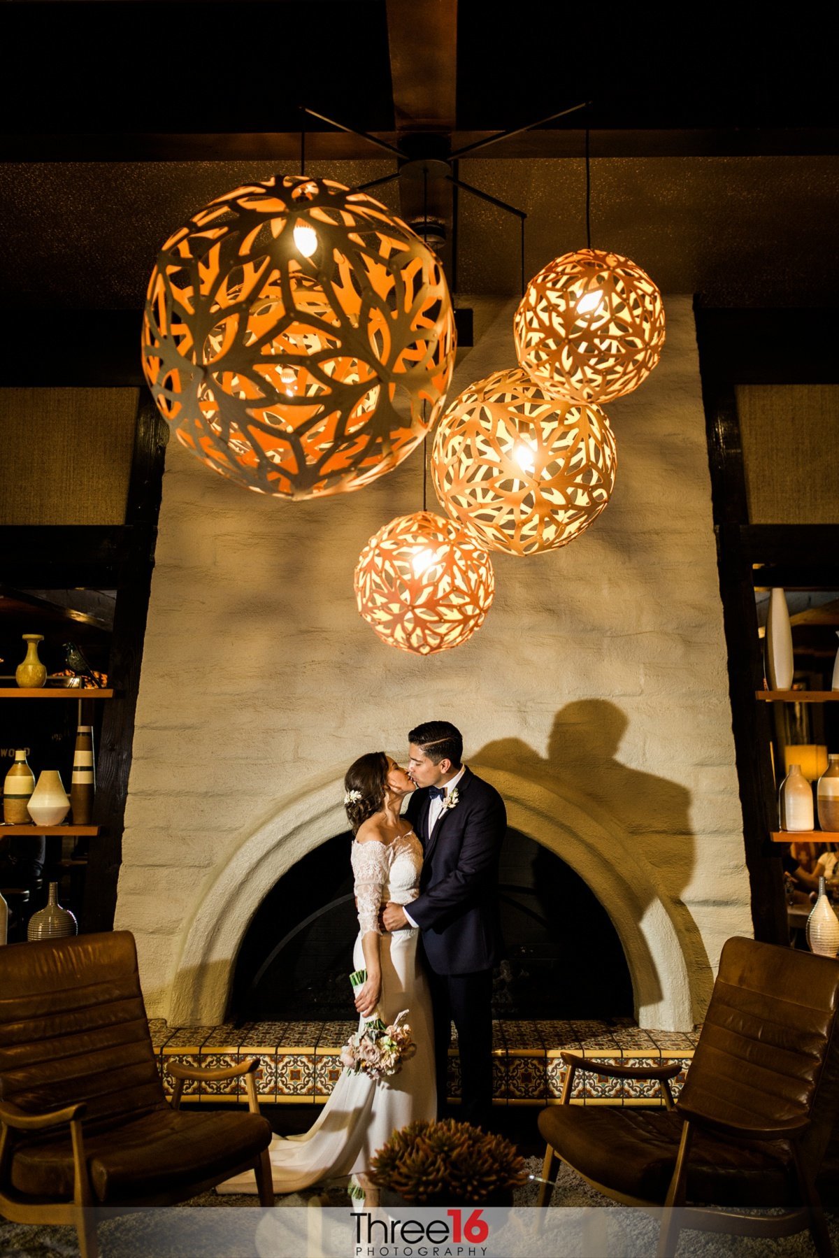 Bride and Groom kiss in front of a large fireplace