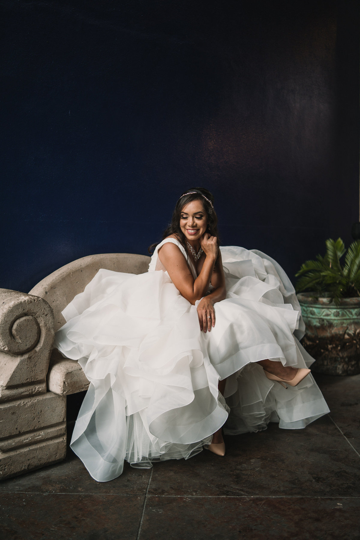 Bride sitting on a concrete bench posing for her bridal pictures at a hotel venue in downtown San Antonio.
