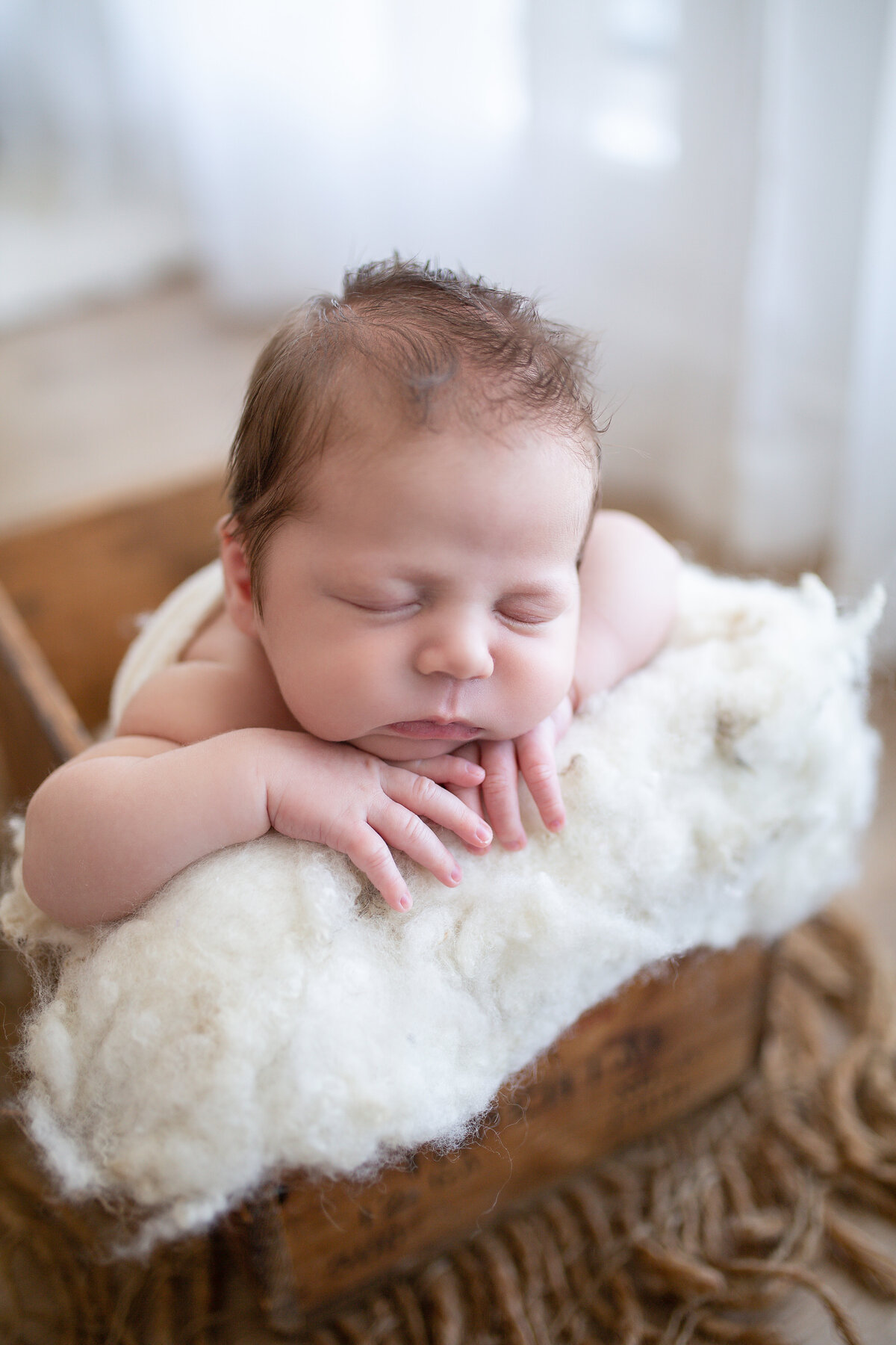 newborn boy posed with head in hands