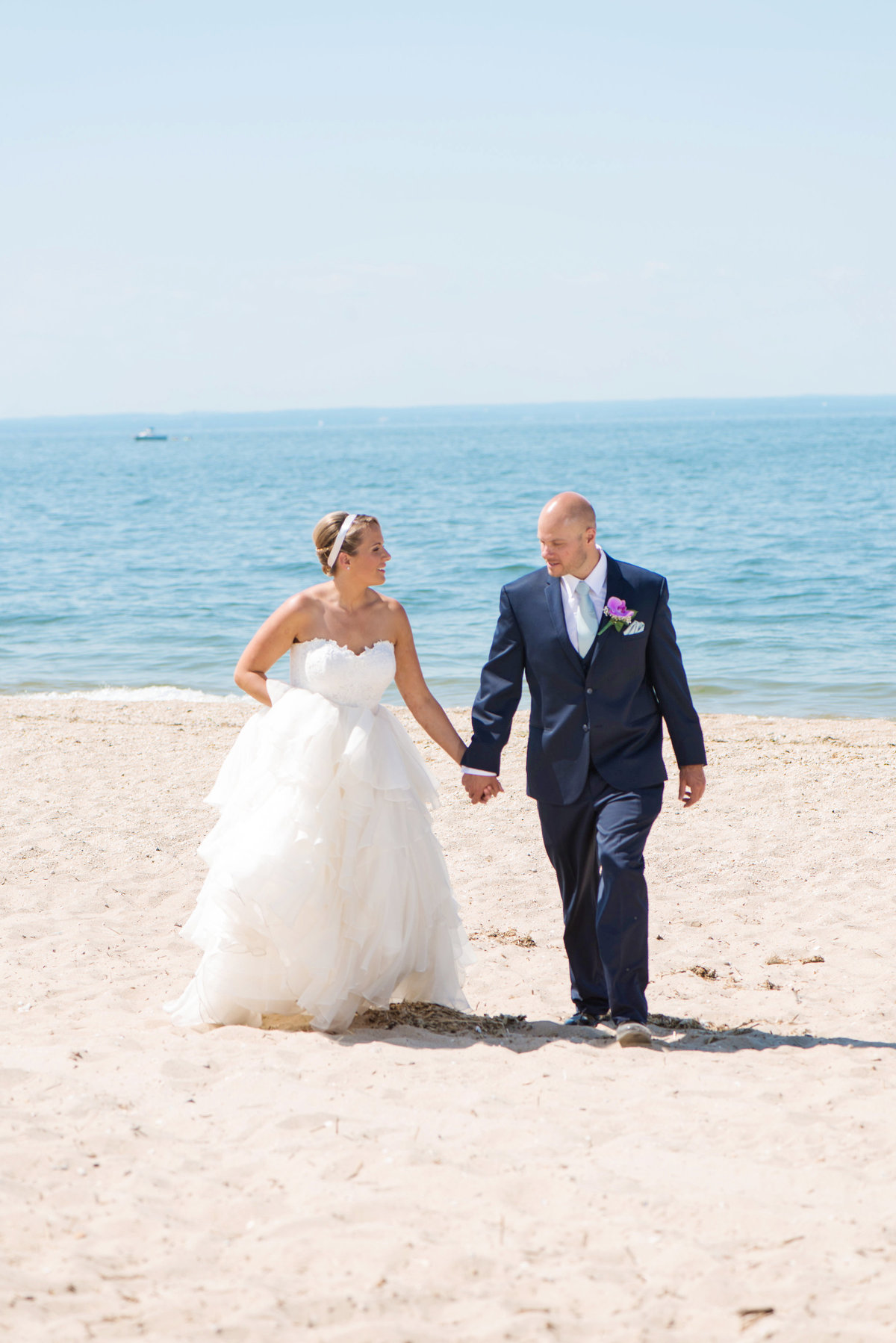 photo of bride and groom walking down the beach from wedding at Pavilion at Sunken Meadow