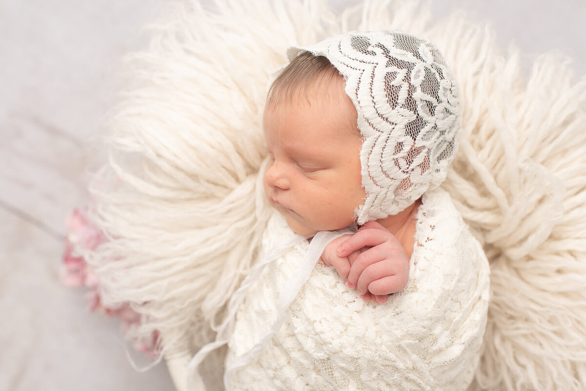 Baby girl dressed in white bonnet at simple indoor newborn photo shoot || Canton, Connecticut