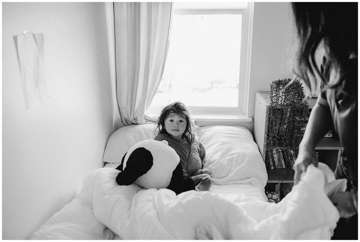 Child in bed holding giant stuffed animal at family photo session in Austin by Amber Vickey Photography